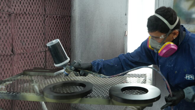 Man spraying dimensional letters with paint in protective gear