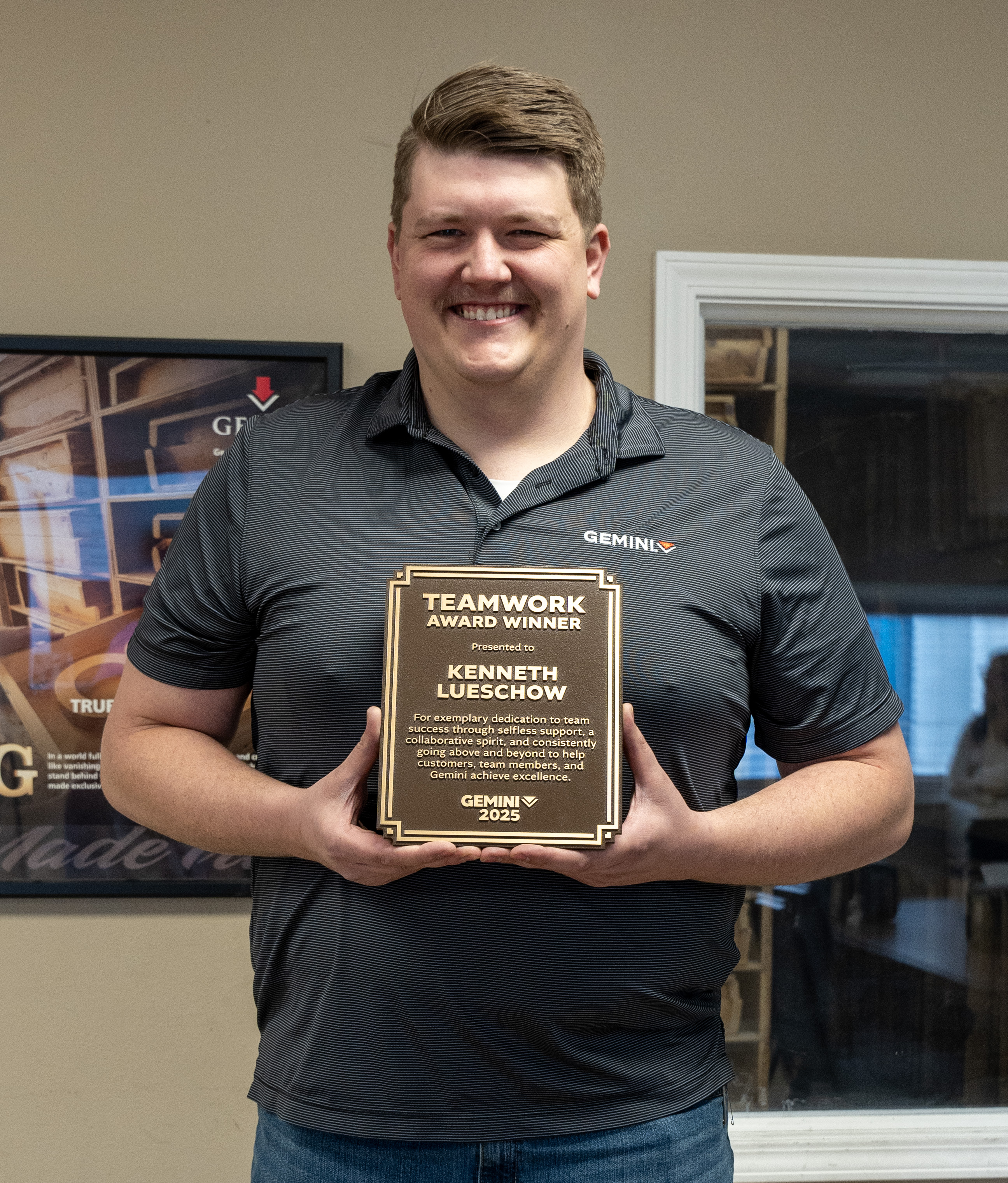 Kenneth Lueschow is smiling while holding the Gemini 2025 Teamwork Award plaque in recognition of his dedication to collaboration and customer success.