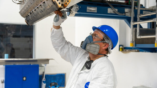 Gemini team member wearing full PPE, including a respirator and hard hat, performing maintenance on equipment, demonstrating safety-first protocols in action.