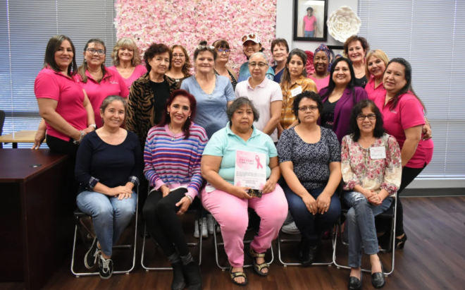 Group of 15 or more women sitting in chairs and smiling at the camera